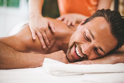 A man smiling while getting a massage in a spa.