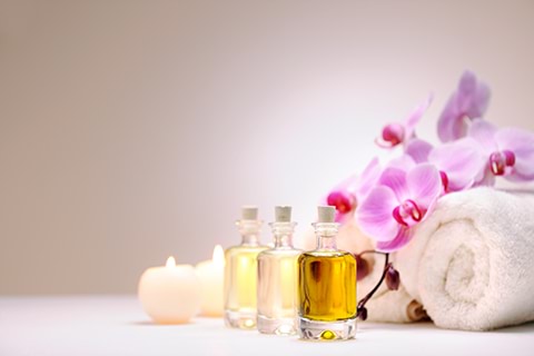 Oils and candles with a towel and orchid beside.