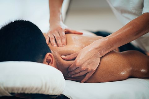 A man getting a back massage from a therapist on a massage table.